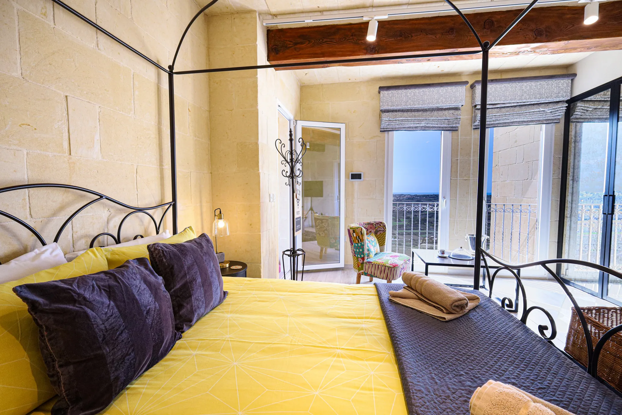 A bedroom with exposed limestone walls and a four-poster bed
